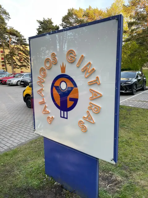 Dvipusis lauko reklaminis stendas ant stovo prie automobilių aikštelės
